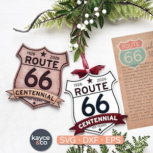 May include: Two Route 66 Centennial ornaments. One is wood-toned, the other white with a red ribbon. Both feature the text "ROUTE 66" and "CENTENNIAL 100 YEARS". A card celebrates 100 years of Route 66.