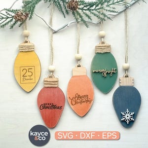 May include: Wooden Christmas light bulb ornaments in yellow, red, orange, green, and blue. Each ornament has a different design, including the date "25 December", the words "Merry Christmas", and a snowflake. The ornaments hang from twine.