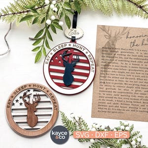 May include: Wooden deer-themed ornaments with the text "EAT SLEEP HUNT REPEAT" and a deer silhouette. One ornament features a red, white, and blue design, while the other is a natural wood color. A card with text about hunting is also present.