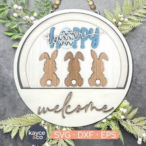 May include: A wooden welcome sign with a white background and a blue and white Easter egg design. The sign says "Happy Easter" and "Welcome" in a decorative font. There are three brown bunny silhouettes on the sign.