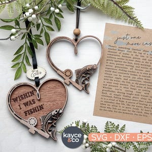 May include: Wooden heart-shaped ornaments with fishing-themed designs. One ornament reads "Wishin' I Was Fishin'" and features a fish and fishing rod. The other has a heart shape with a fish and rod. A card with text is also present.