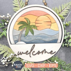 May include: A round wooden sign with a welcome message. The sign features a colorful illustration of a palm tree, sunset, and ocean waves.