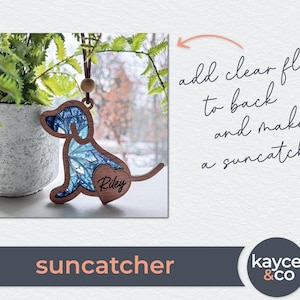 May include: A blue and white stained glass dog suncatcher with the name "Riley" on a heart-shaped tag. The suncatcher is hanging from a brown cord.
