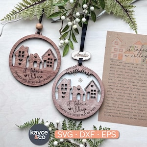 May include: Two wooden ornaments with a house design and the text "it takes a village". One ornament has the text "Thanks for being part of ours". The other has the name "Amelia" and the text "Thanks for being part of mine".