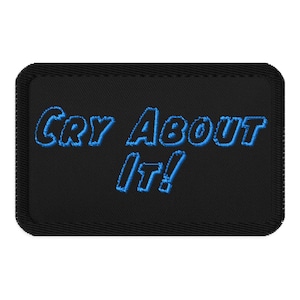 Pode incluir: Etiqueta bordada preta com texto azul que diz "Cry About It!"