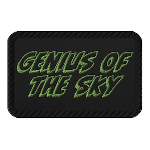 Op de afbeelding: Zwarte geborduurde patch met groene tekst die "Genius of the Sky" luidt.