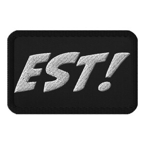 Könnte beinhalten: Schwarzer gestickter Aufnäher mit weißem Text, der "EST!" lautet.
