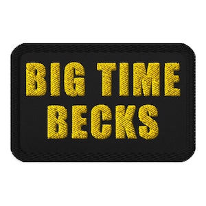 May include: Black rectangular patch with the words "BIG TIME BECKS" embroidered in yellow thread. The patch has a black border and a textured appearance.