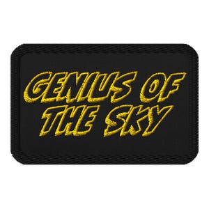 Op de afbeelding: Zwarte geborduurde patch met gele tekst die "Genius of the Sky" luidt.