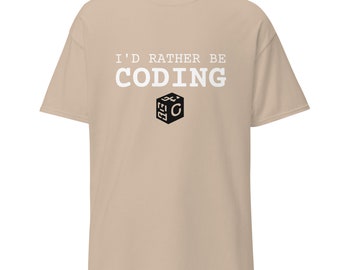 Può includere: Una t-shirt beige con il testo "I'd rather be coding" in lettere bianche e un cubo bianco e nero con la lettera "C" all'interno.