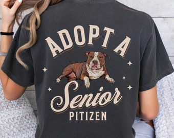 May include: Black t-shirt with the text "Adopt a Senior Pitizen" in a vintage font. A brown and white pit bull dog is pictured lying down in front of the text.