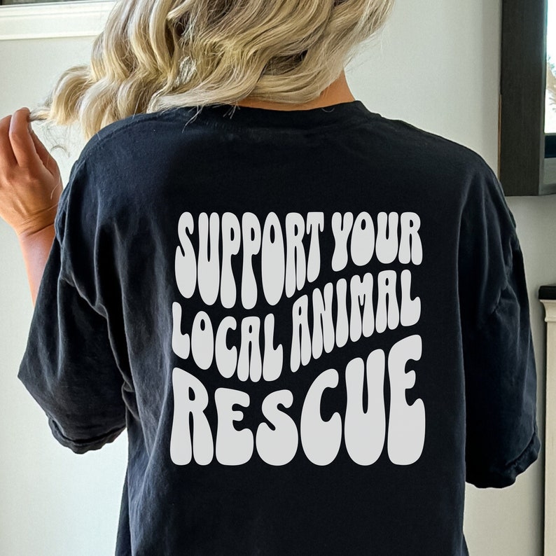 May include: Black t-shirt with white text that reads "Support Your Local Animal Rescue" in a retro font.