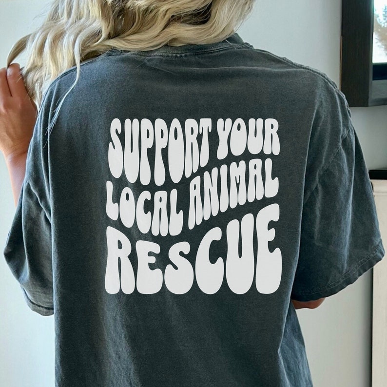 May include: A dark gray t-shirt with the text "SUPPORT YOUR LOCAL ANIMAL RESCUE" in white, retro-style lettering.