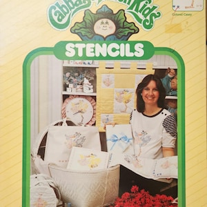 May include: Package of Cabbage Patch Kids stencils featuring a yellow and white quilt with a stork design. The package includes two 8 1/2 by 11 inch stencil sheets. The text on the package reads "Quality Stencils of Mylar* for Home & Fashion Decor".