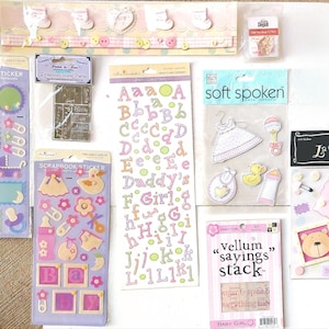 May include: A collection of baby girl scrapbook stickers featuring a variety of designs, including letters, animals, and baby items. The stickers are in pink, yellow, and green colors. The text on the stickers includes "Daddy's Girl", "Baby Girl", and "Soft Spoken".