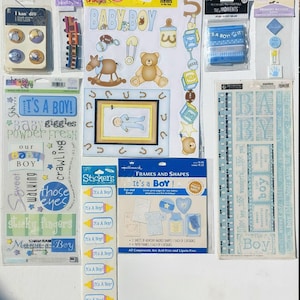 May include: A collection of scrapbook supplies with a baby boy theme. Includes stickers, frames, and embellishments in blue, yellow, and brown. Text includes "It's a Boy!" and "Baby Boy."