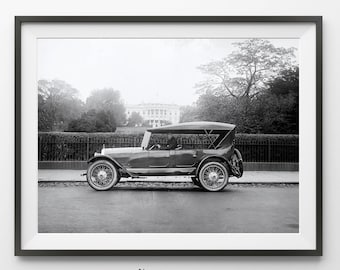 May include: Black and white framed print of a vintage car parked on a street with the White House in the background. The car has a convertible top and spoked wheels. The print is from L'amour Art Studio.