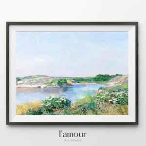 May include: Framed landscape art print featuring a serene coastal scene. The artwork depicts a calm blue body of water surrounded by lush greenery, rocky shores, and a clear blue sky. The print is framed in a black frame, with the text "l'amour Art Studio" at the bottom.