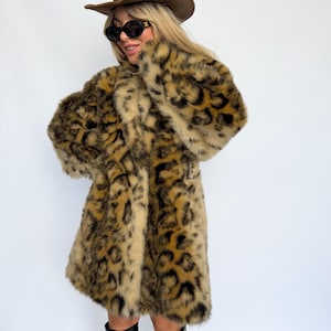 May include: A long-sleeved faux fur coat featuring a brown and black leopard print pattern, paired with a brown suede cowboy hat, black oval-framed sunglasses, and black knee-high boots, creating a bold and textured ensemble.