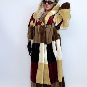 Può includere: Un lungo cappotto con cappuccio con un design patchwork nei toni del marrone, beige, nero e bordeaux. Il cappotto ha una chiusura con un solo bottone e una morbida texture in ecopelliccia. Stile vintage.
