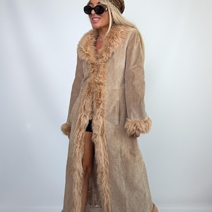 May include: A long, tan suede coat featuring a thick, fluffy faux fur trim along the collar, front opening, cuffs, and hem. The coat is paired with a leopard print beret and dark-tinted oval sunglasses, creating a cohesive, textured ensemble.