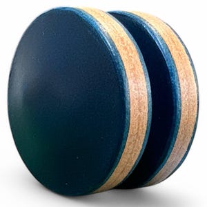 May include: A pair of wooden plugs with a dark blue face and a light brown, layered edge. The plugs are round and appear to be made of multiple layers of wood. The edges have a thin blue line.
