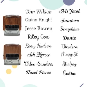 May include: Two self-inking stamps with a wood-grain finish and clear bases, labeled Trodat Printy T1438. Beside them are two columns of names in various black fonts: Tom Wilson, Quinn Knight, Jesse Bowen, Riley Cox, Remy Hudson, Ash Mercer, Chloe Sanders, Hazel Pierce, Ms Jacob, Sanders, Seraphina, Dante, Theodora, Marigold, Sterling, and Ondine.