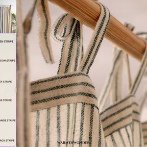 May include: Close-up of a set of striped curtains hanging on a wooden rod. The curtains are in various colours, including green, maroon, grey, blue, orange, and black. The text "WARMTH WONDER" is visible at the bottom of the image.