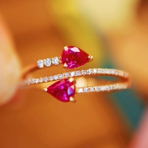 Peut inclure: Une bague en or avec deux rubis en forme de poire et une bande de petits diamants.