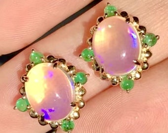 Puede incluir: Un par de pendientes de ópalo de forma ovalada engastados en oro con un halo de piedras preciosas verdes.