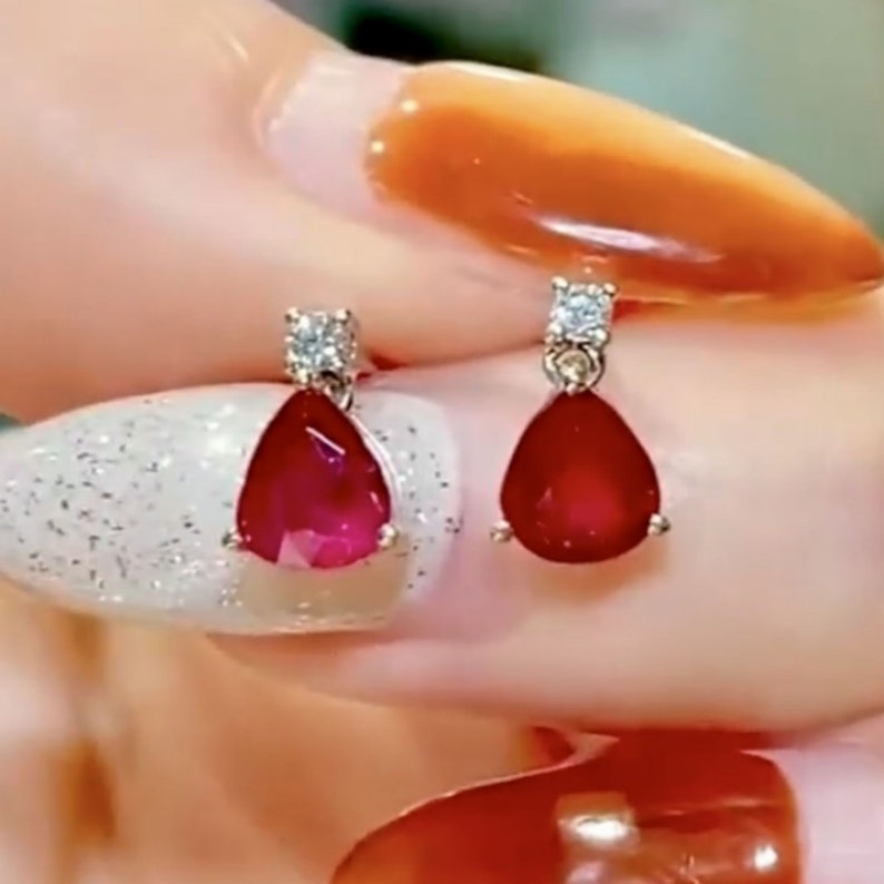 Pu&ograve; includere: Un paio di orecchini a goccia di rubino con un singolo accento di diamante su ogni orecchino.