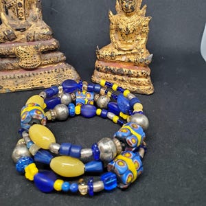 May include: A multi-strand bracelet with blue and yellow glass beads, silver beads, and yellow stone beads.