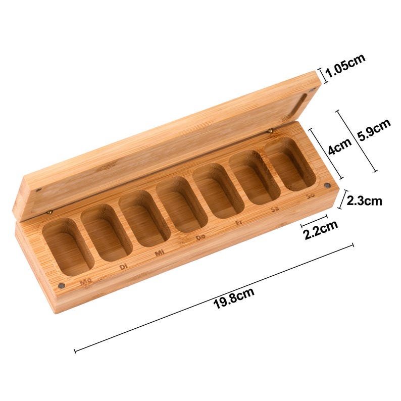 K&ouml;nnte beinhalten: Ein rechteckiger Pillen-Organizer aus Bambus mit Scharnierdeckel. Die offene Box zeigt sieben F&auml;cher, die f&uuml;r jeden Wochentag beschriftet sind. Die Box ist 19,8 cm lang, 2,3 cm hoch und 5,9 cm breit. Der Deckel ist 1,05 cm dick.