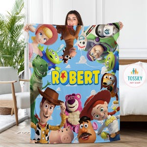 以下が含まれることがあります： ウッディ、バズ・ライトイヤー、ジェシー、レックスなど、トイ・ストーリーのキャラクターが描かれた青と黄色の毛布。毛布には「ROBERT」という名前が黄色い文字で星と一緒に印刷されています。