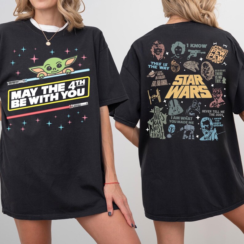 K&ouml;nnte beinhalten: Schwarzes T-Shirt mit einem Baby Yoda-Motiv, Lichtschwertern und dem Text "MAY THE 4TH BE WITH YOU". Auf der R&uuml;ckseite des Shirts befinden sich Illustrationen und Zitate von Star Wars-Charakteren. L&auml;ssiger, &uuml;bergro&szlig;er Schnitt.