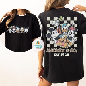 May include: Black t-shirt featuring a graphic of Mickey Mouse and friends. The front of the shirt displays the characters, while the back showcases a checkered design with the text "Mickey & Co. EST.1928".