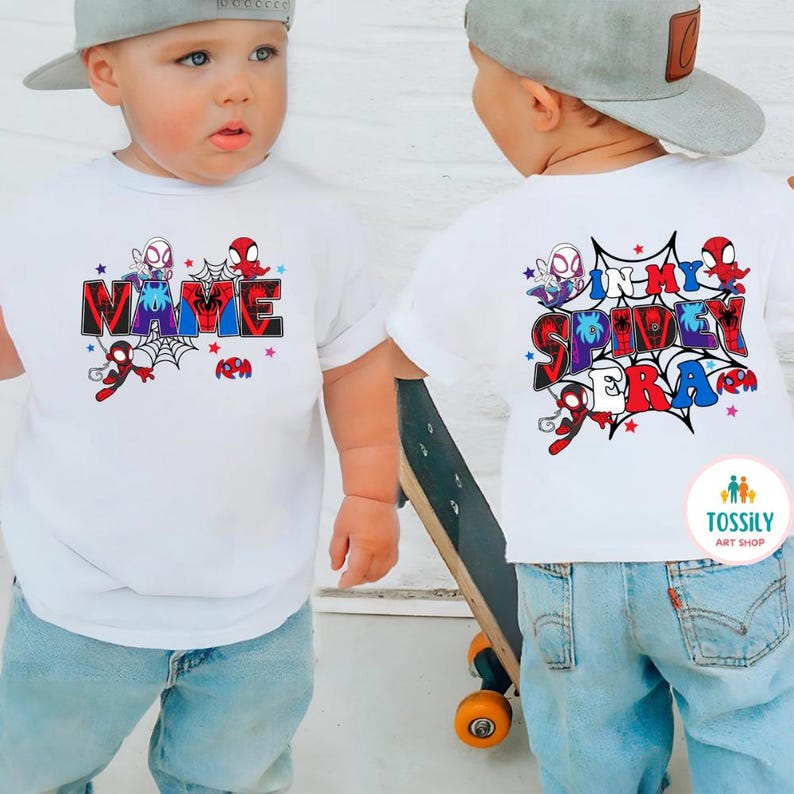 K&ouml;nnte beinhalten: Wei&szlig;e T-Shirts mit Spider-Man-Motiv. Auf der Vorderseite des Shirts steht das Wort "NAME" im Comic-Stil mit Spider-Man-Grafiken. Auf der R&uuml;ckseite des Shirts steht "IN MY SPIDEY ERA" mit Spider-Man-Grafiken. Die Shirts werden von einem Kind getragen.