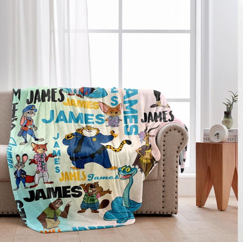 K&ouml;nnte beinhalten: Eine personalisierte Fleece-Decke mit Cartoon-Figuren und dem Namen "JAMES" in verschiedenen Schriftarten. Die Decke hat ein hellblaues, gr&uuml;nes und rosa Farbschema mit Bildern von Tieren in verschiedenen Outfits.