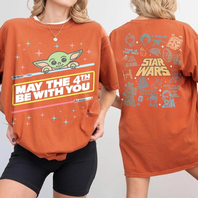 K&ouml;nnte beinhalten: Gebrannt orangefarbenes T-Shirt mit einer Baby Yoda-Grafik, Lichtschwertern und dem Text "MAY THE 4TH BE WITH YOU". Auf der R&uuml;ckseite des Shirts sind Star Wars-Charaktere und -Phrasen abgebildet. Ein l&auml;ssiges T-Shirt f&uuml;r Star Wars-Fans.