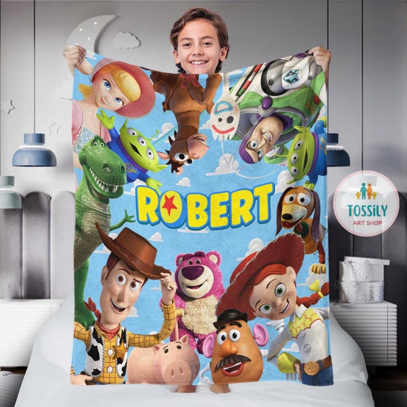 以下が含まれることがあります： トイストーリーをテーマにした青と緑のフリースブランケット。ブランケットには、ウッディ、バズ・ライトイヤー、ミスター・ポテトヘッドなどのキャラクターが描かれています。ブランケットには「ROBERT」という名前が黄色の文字で印刷されています。