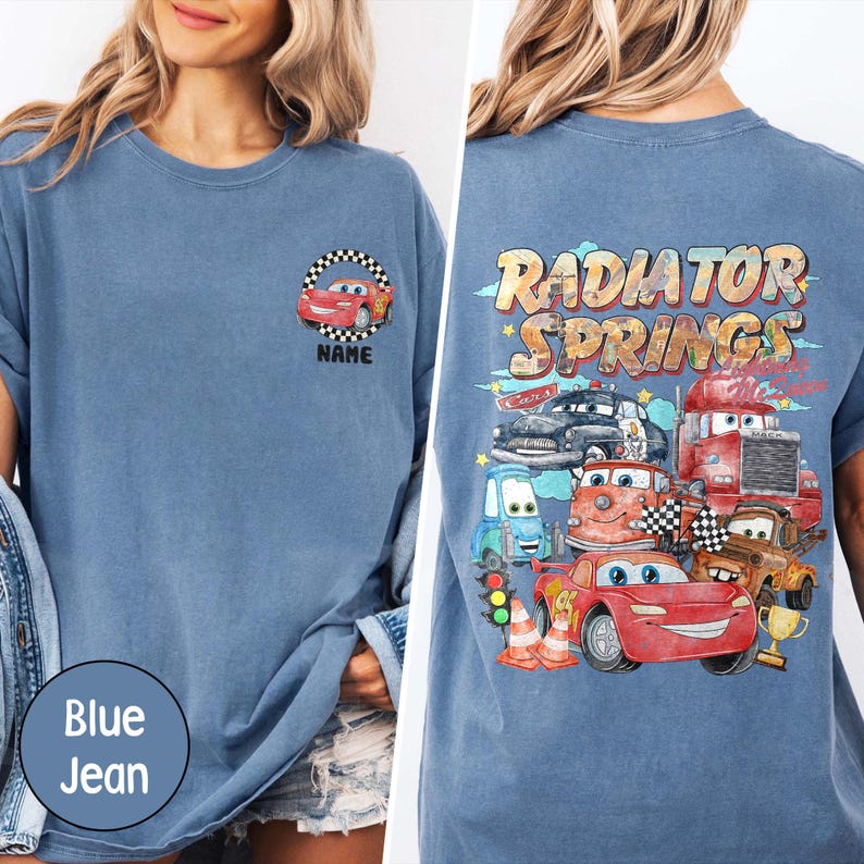 Puede incluir: Camiseta azul vaquera con un dise&ntilde;o de coche de dibujos animados en la parte delantera y un gr&aacute;fico de "Radiator Springs" en la parte trasera. El dise&ntilde;o incluye coches de dibujos animados, banderas a cuadros y el texto "NAME".