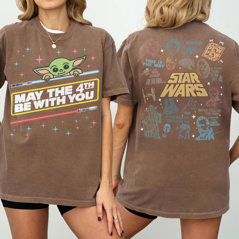 K&ouml;nnte beinhalten: Braunes T-Shirt mit einem Baby Yoda-Motiv und dem Text "MAY THE 4TH BE WITH YOU" auf der Vorderseite. Die R&uuml;ckseite zeigt Illustrationen und Zitate von Star Wars-Charakteren. Das T-Shirt hat einen Rundhalsausschnitt.