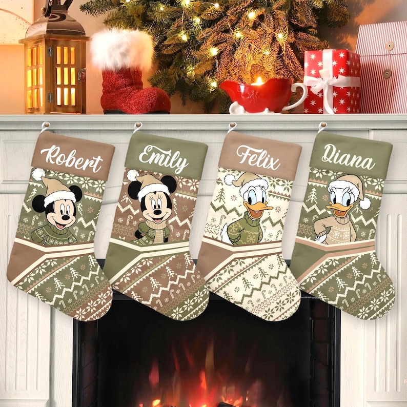 May include: Four Christmas stockings with personalized names: Robert, Emily, Felix, and Diana. Each stocking features a Disney character in a winter outfit. The stockings have a green and brown patterned design with a white cuff.