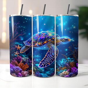 May include: A set of three stainless steel tumblers with a vibrant underwater scene. The design features a colorful sea turtle swimming among coral and starfish. The tumblers have a dark blue background with bubbles and a black straw.