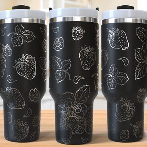 Puede incluir: Tres tazas de viaje de acero inoxidable negro con un diseño blanco de fresas y hojas. Las tazas tienen un asa y una tapa. El texto "SEAMLESS DESIGN" es visible en la esquina inferior derecha de la imagen.