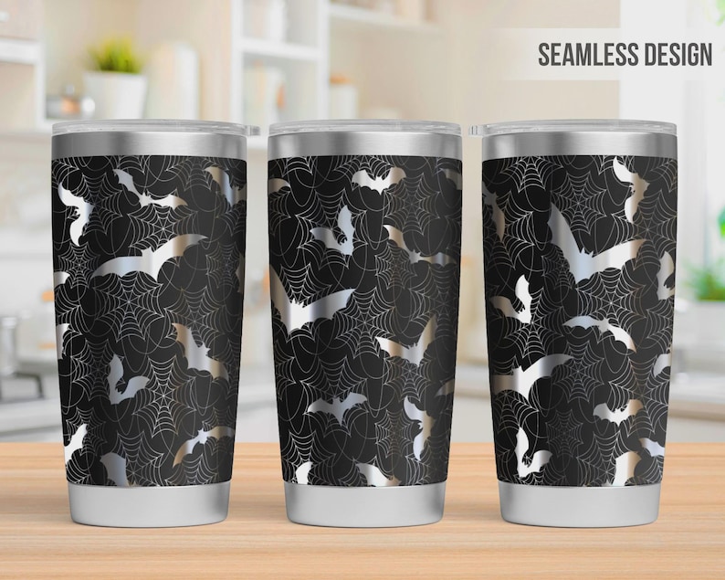 Pu&ograve; includere: Tre bicchieri in acciaio inossidabile con un design senza cuciture di pipistrelli argentati e ragnatele bianche su sfondo nero. Ogni bicchiere ha un coperchio trasparente e una base argentata, con un motivo ripetitivo di pipistrelli e ragnatele.