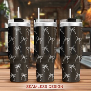 May include: Three stainless steel tumblers with black lids and handles. Each tumbler features a white bow pattern on a black background. The text "SEAMLESS DESIGN" is printed below the tumblers.