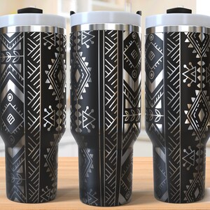May include: Three stainless steel travel mugs with black and silver geometric patterns. The mugs have lids and handles.