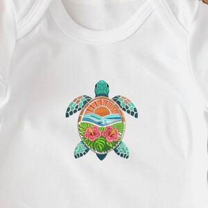 May include: White baby onesie with a colorful sea turtle design. The turtle features a teal head and flippers, with a design of a sunset, waves, and hibiscus flowers on its shell. The onesie is made of soft, white fabric.
