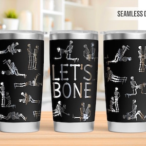 May include: Black stainless steel tumbler with a repeating pattern of silver skeletons in various poses. The center tumbler has the text "LET'S BONE" in white and silver. The tumbler has a seamless design.